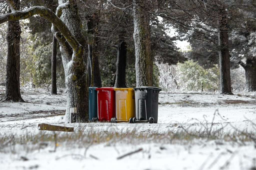 A group of colorful trash cans sitting in the snow.