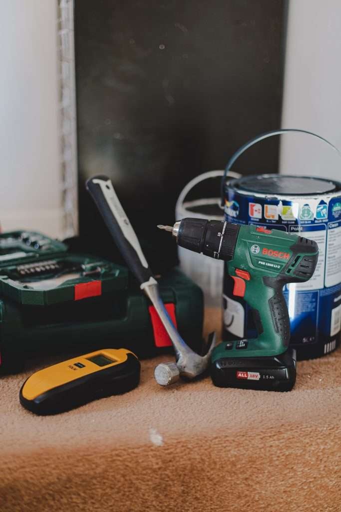 A cordless drill and other tools on a table.