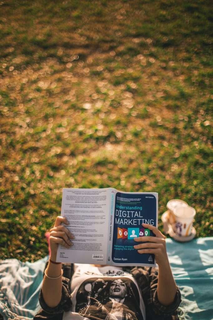 A person laying on the grass reading a book.